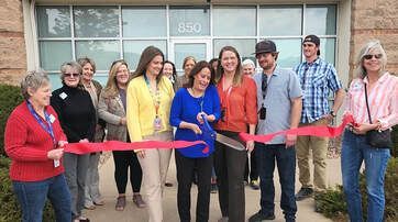 Group of people cutting a red ribbon in front of a building with the number 850, celebrating an opening.