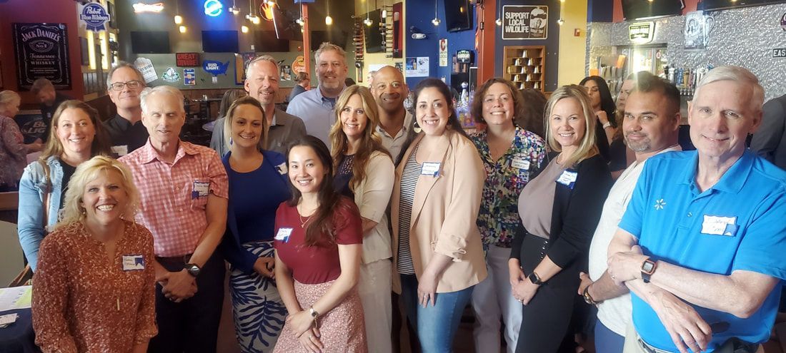Group of people smiling at a restaurant. Several wear name tags.