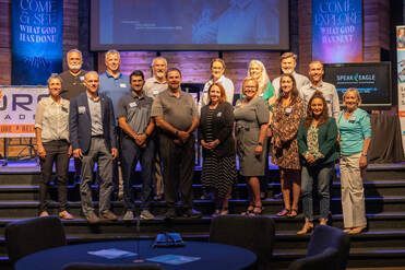 Group of diverse people standing on stage, smiling.