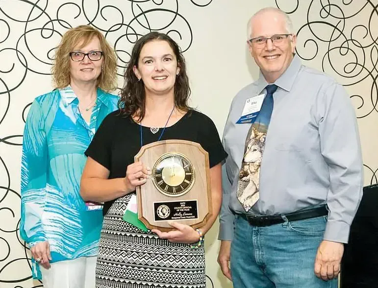 A woman is holding a plaque while standing next to two men.