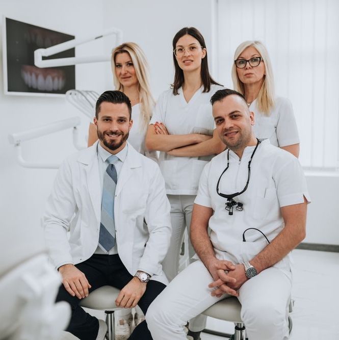 A group of dentists are posing for a picture in a dental office.