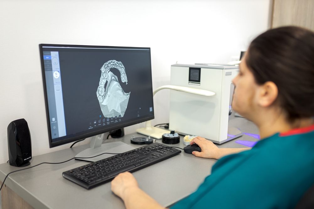 A woman is sitting at a desk using a computer, feeling safe with managed it services for their dental practice