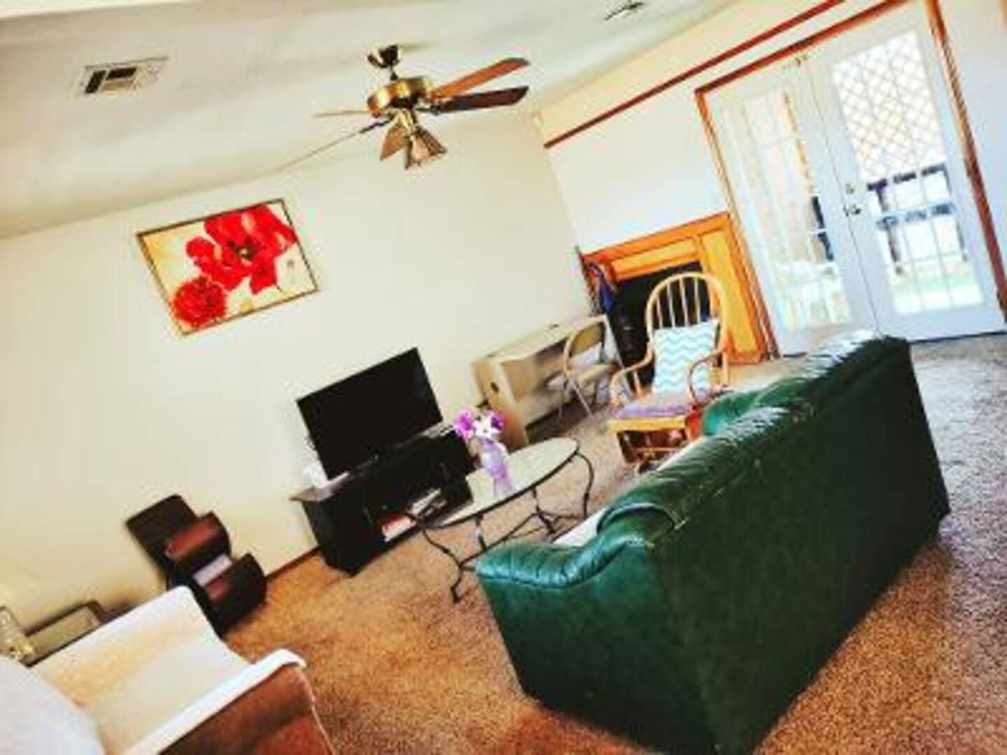 A living room with a green couch and a ceiling fan