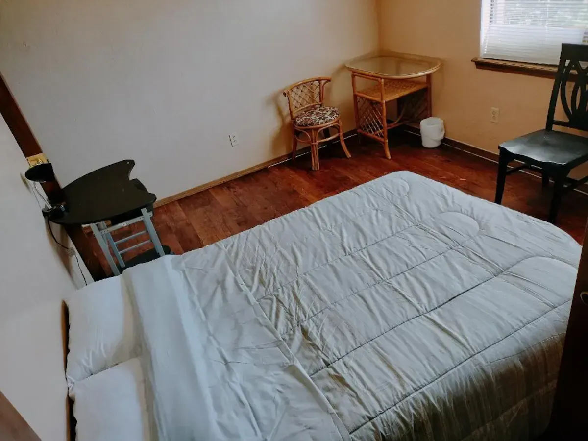 A bedroom with a bed a chair and a desk