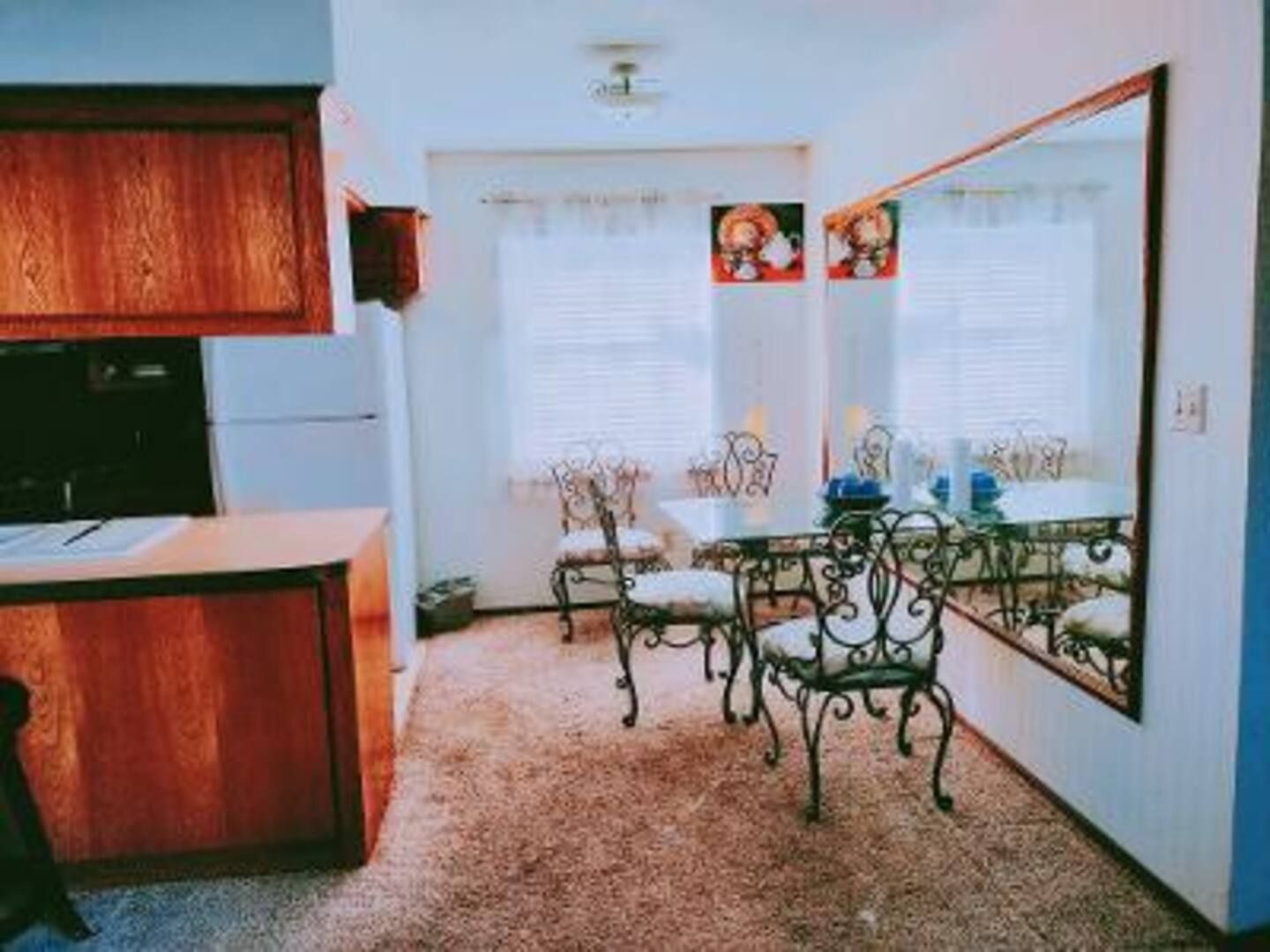 A dining room with a table and chairs and a large mirror on the wall.