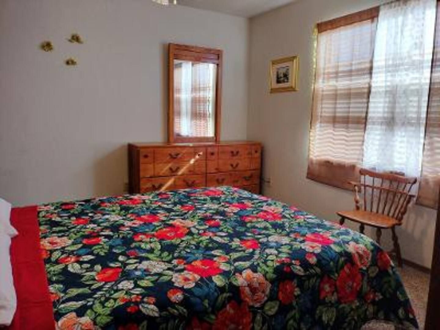 A bedroom with a bed , dresser , mirror and chair