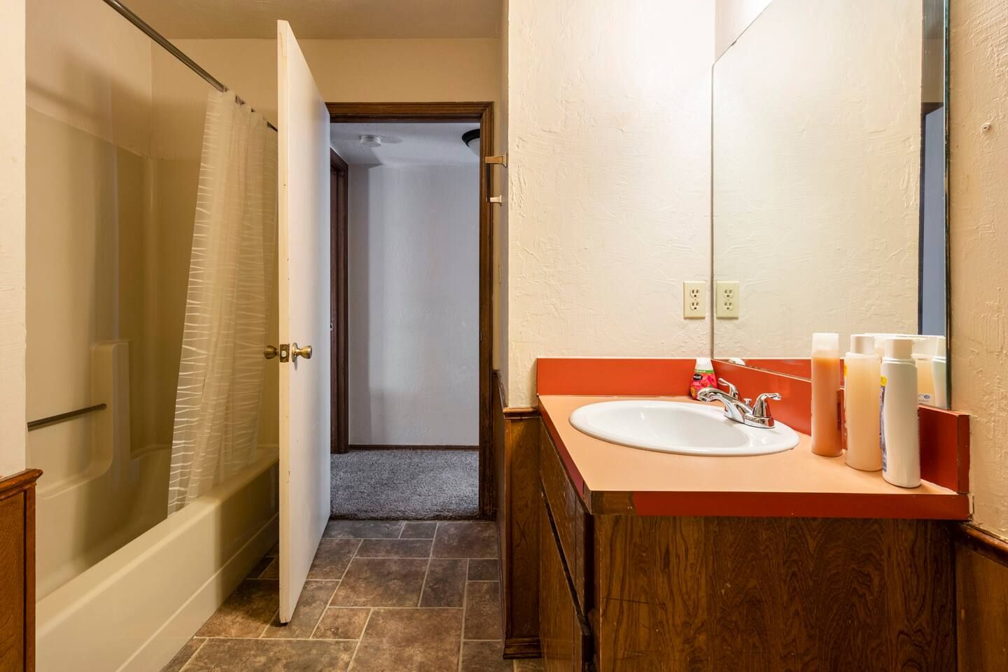 A bathroom with a sink , mirror and tub.