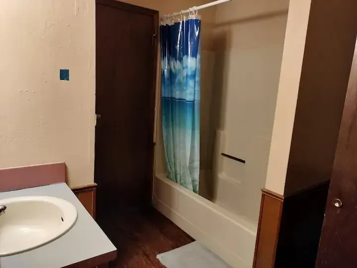 A bathroom with a blue shower curtain and a sink