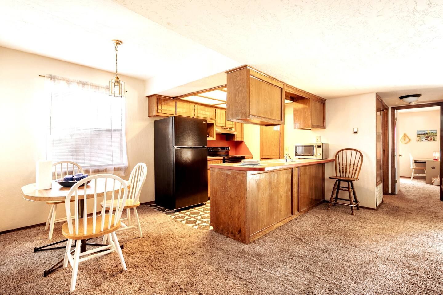 A kitchen with a table and chairs and a refrigerator