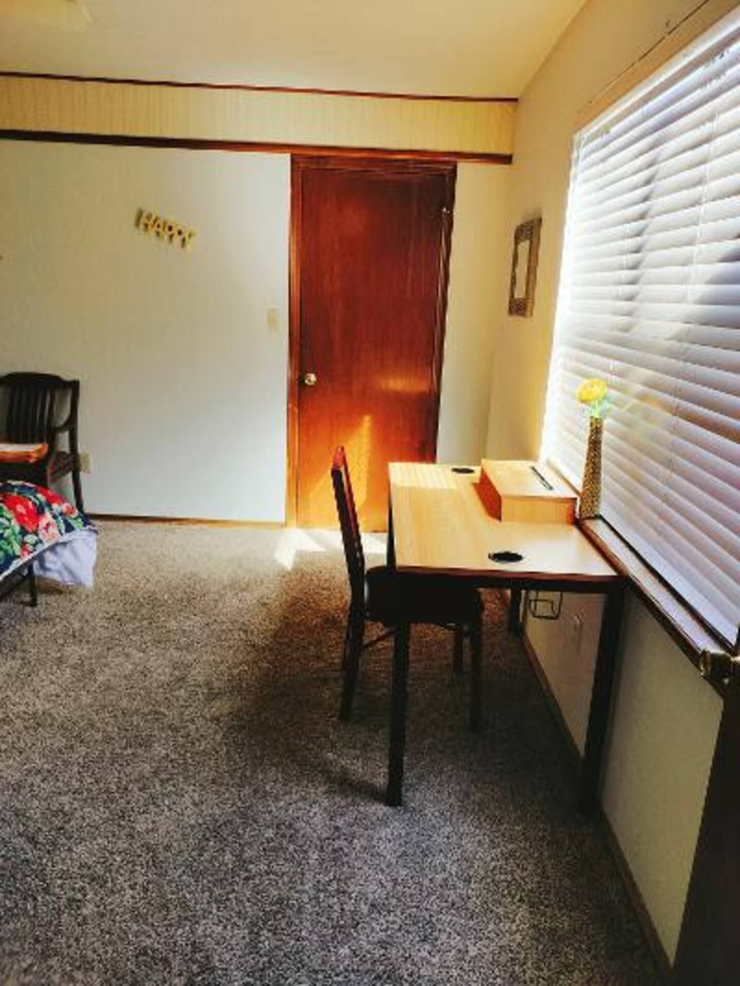A room with a desk and chairs and a sign on the wall that says happy