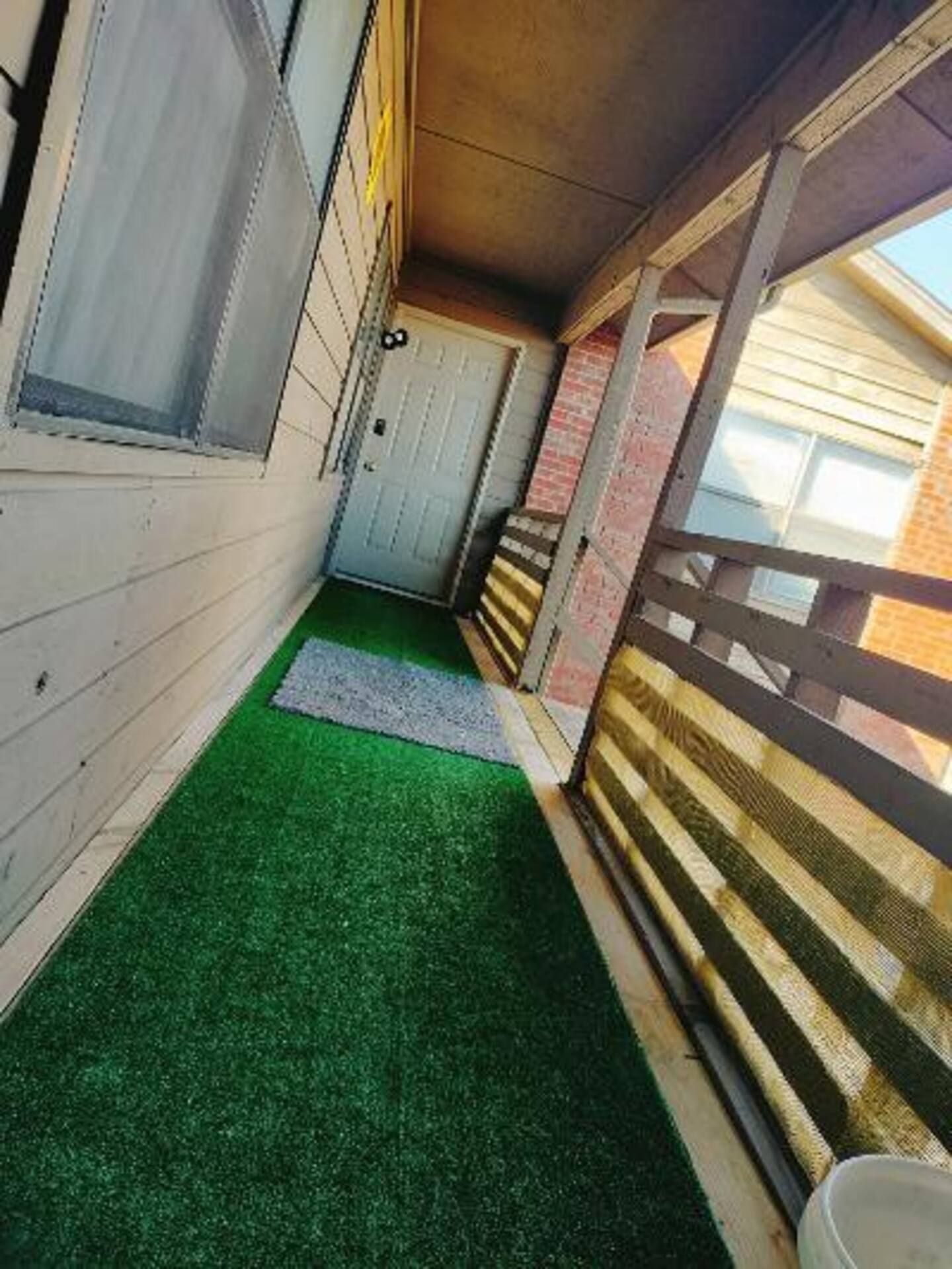 A hallway between two buildings with a green rug on the floor.