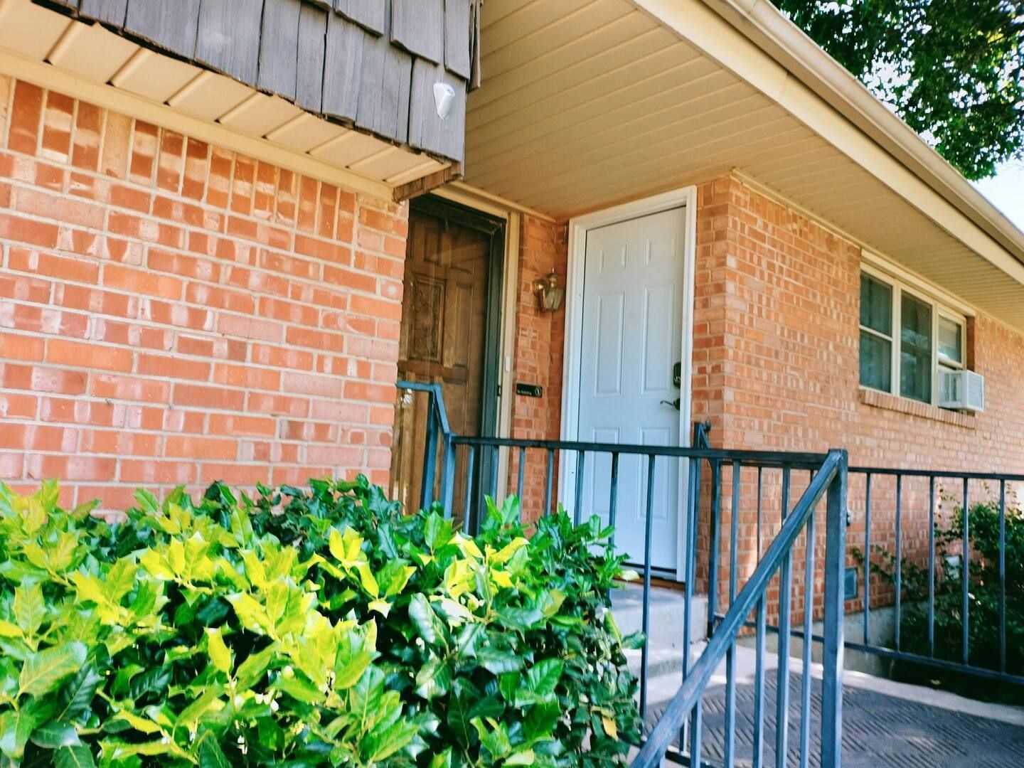 A brick house with a blue door and stairs
