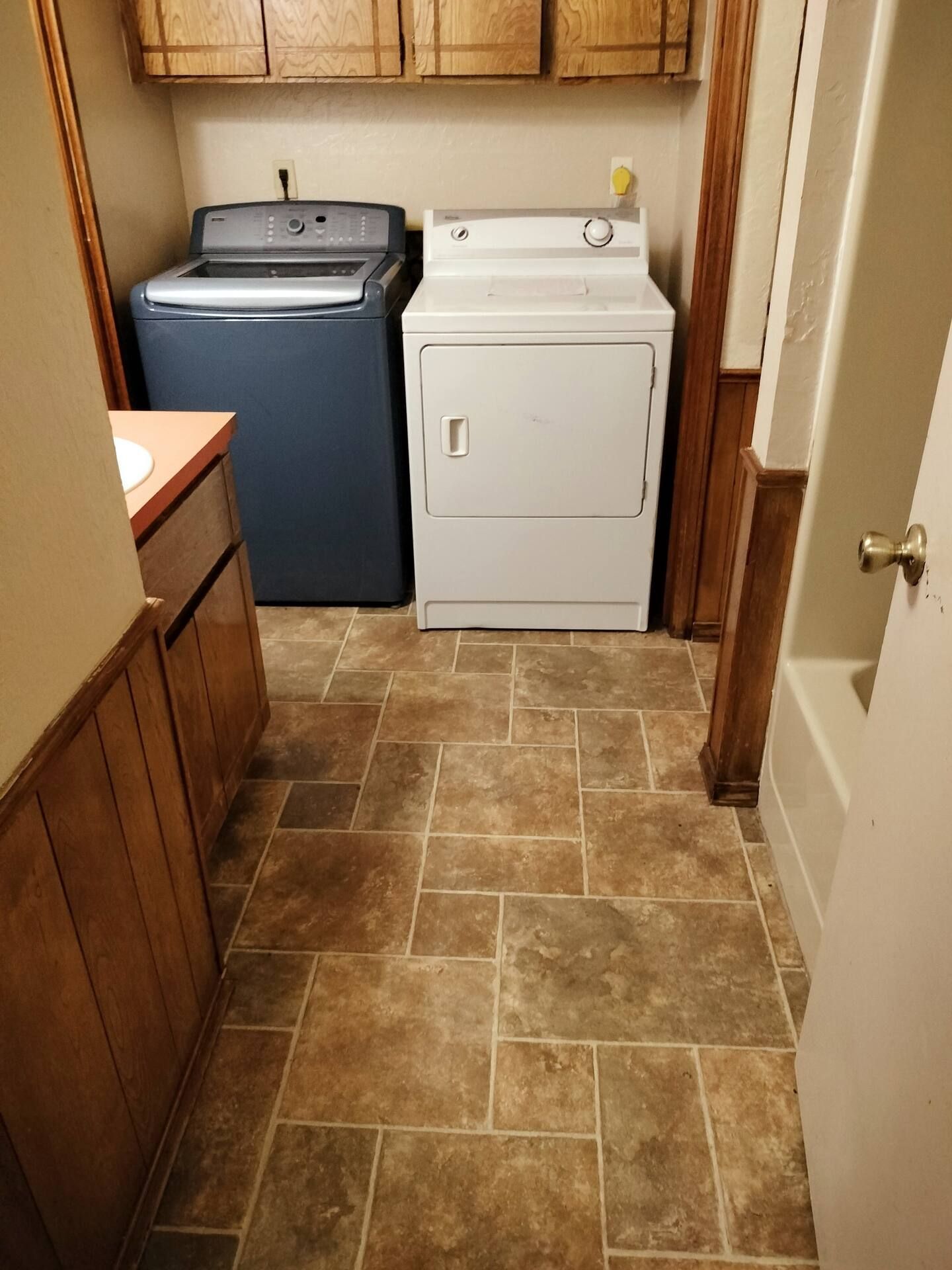 A laundry room with a washer and dryer and a bathtub.