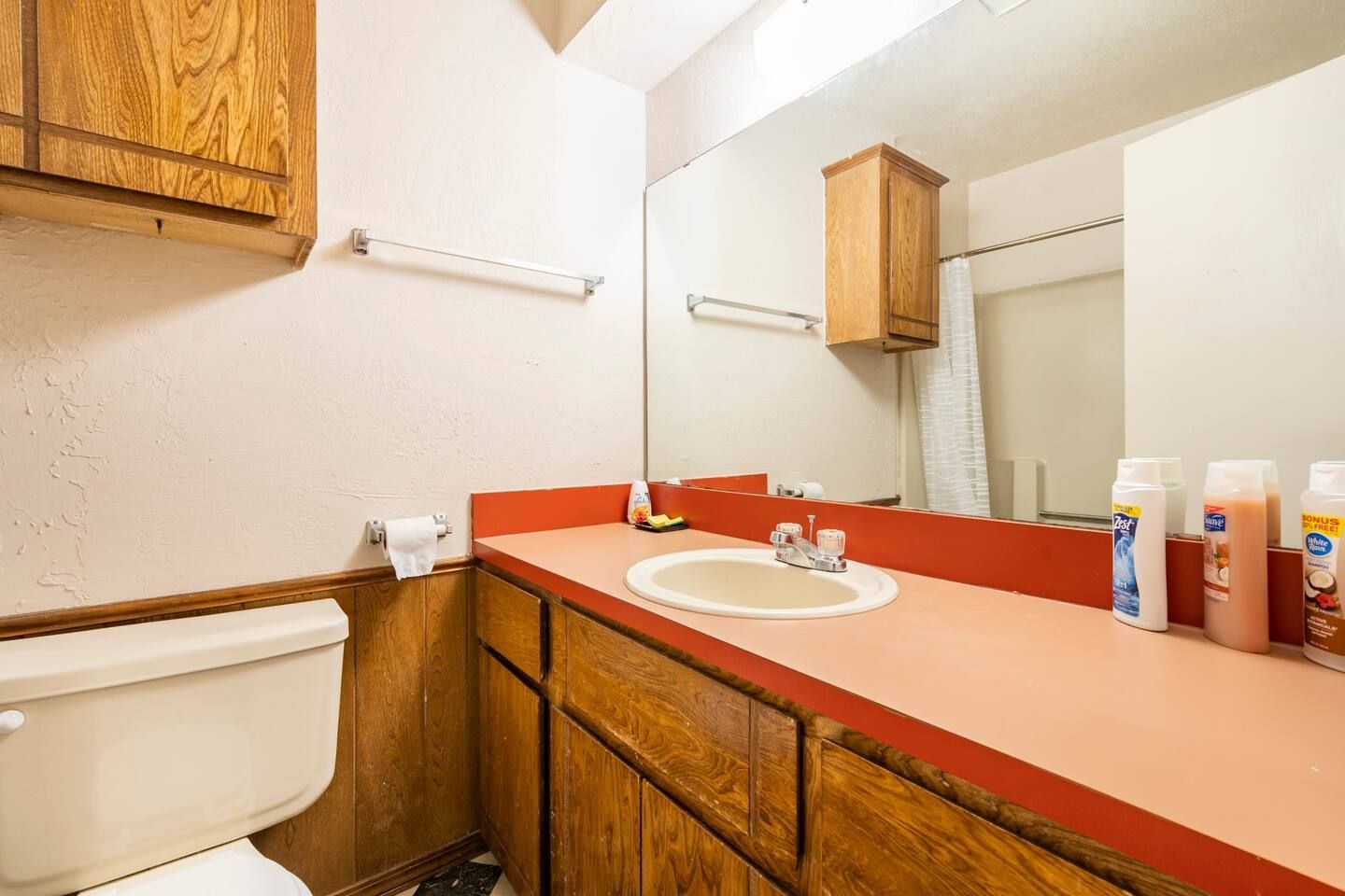 A bathroom with a toilet , sink , and mirror.
