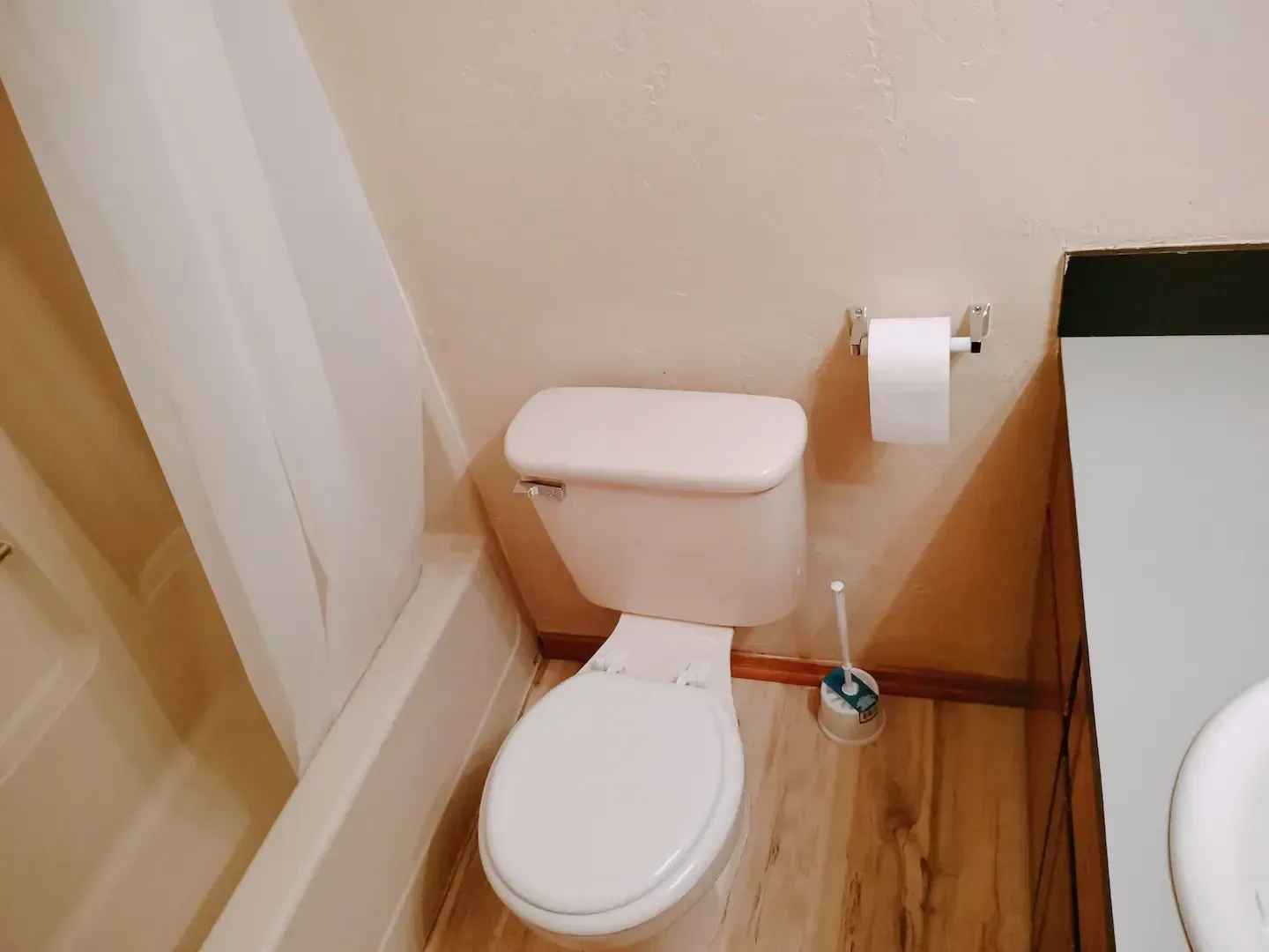 A bathroom with a toilet , sink and shower.