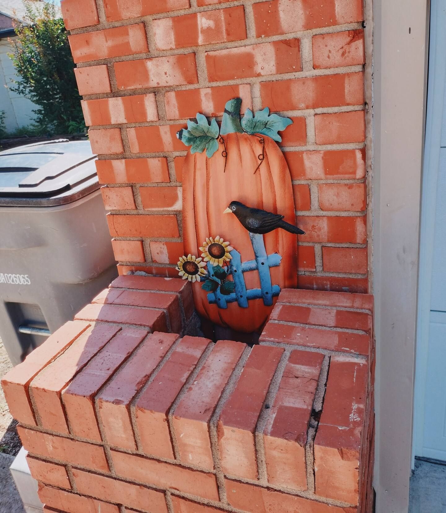 A brick wall with a pumpkin and a bird on it