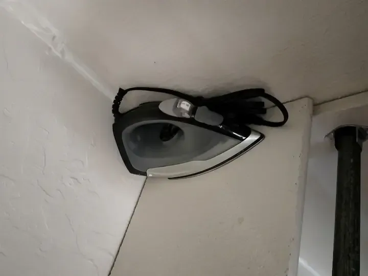 A small iron is sitting on a white wall
