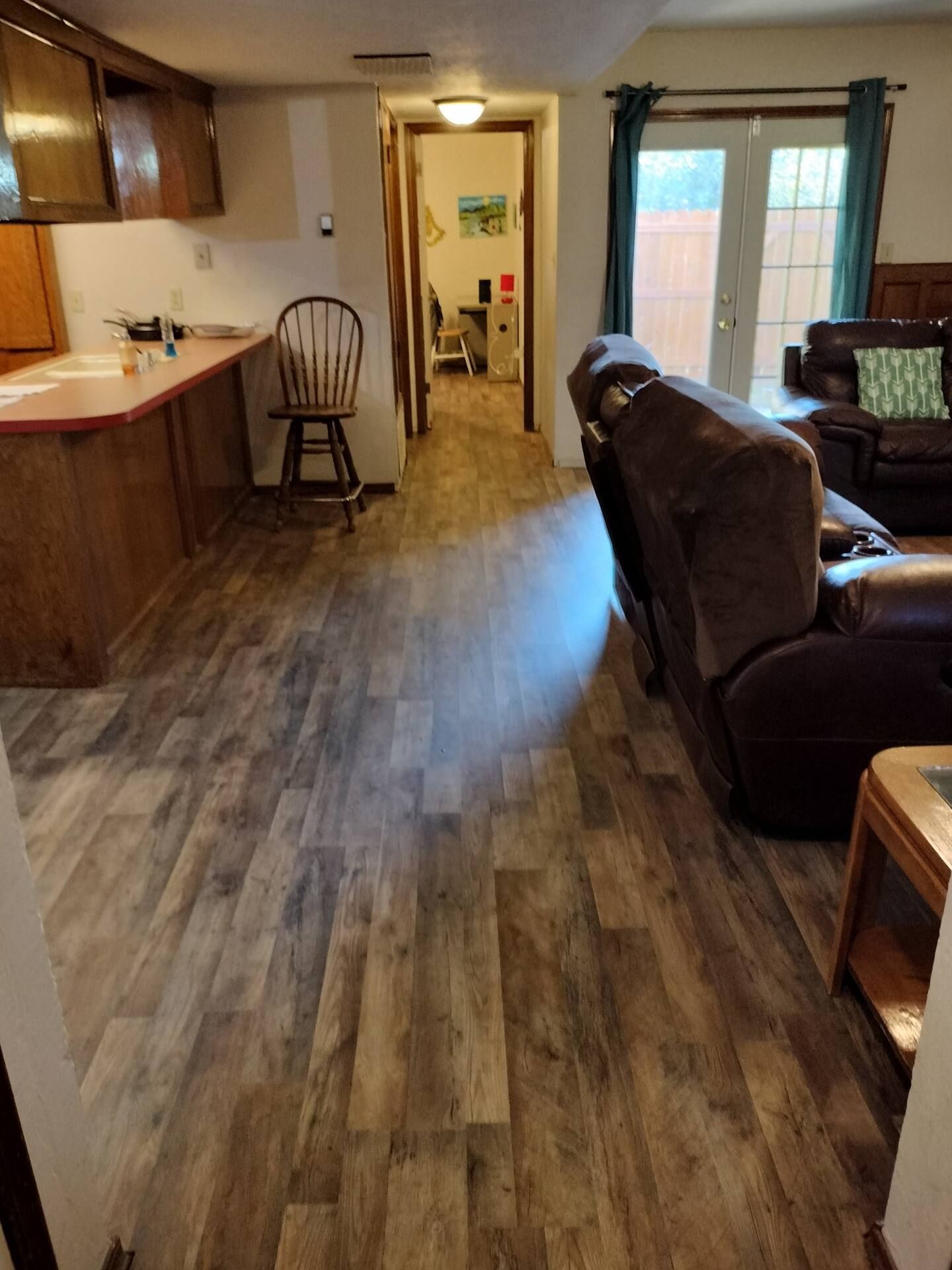 A living room with hardwood floors , a couch , a chair and a table.