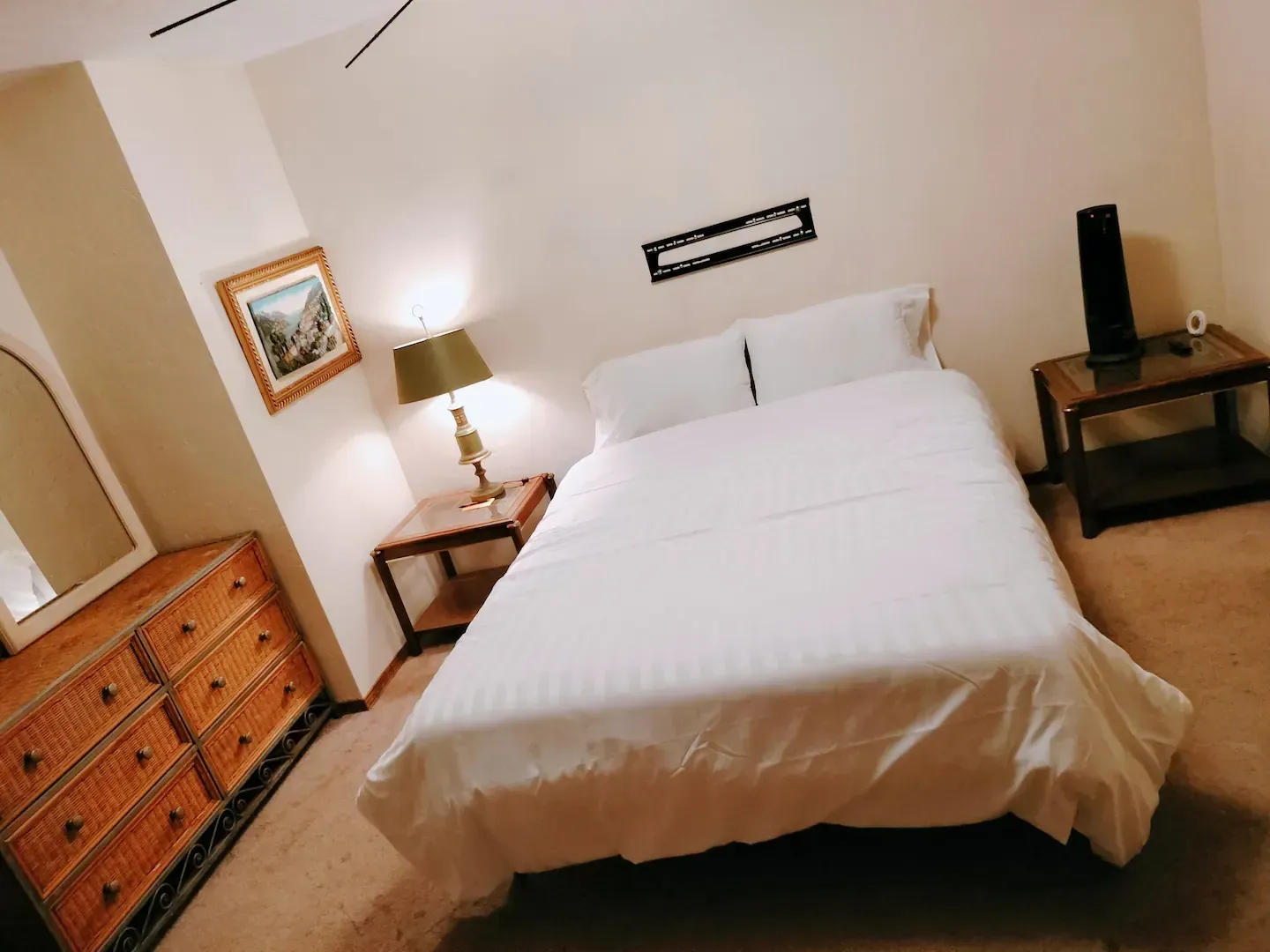 A bedroom with a bed dresser and lamp