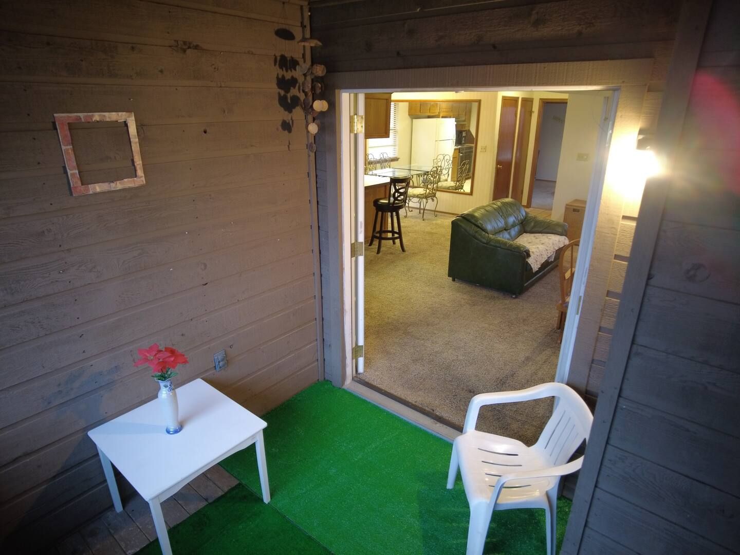 A patio with a chair and a table with a vase of flowers on it