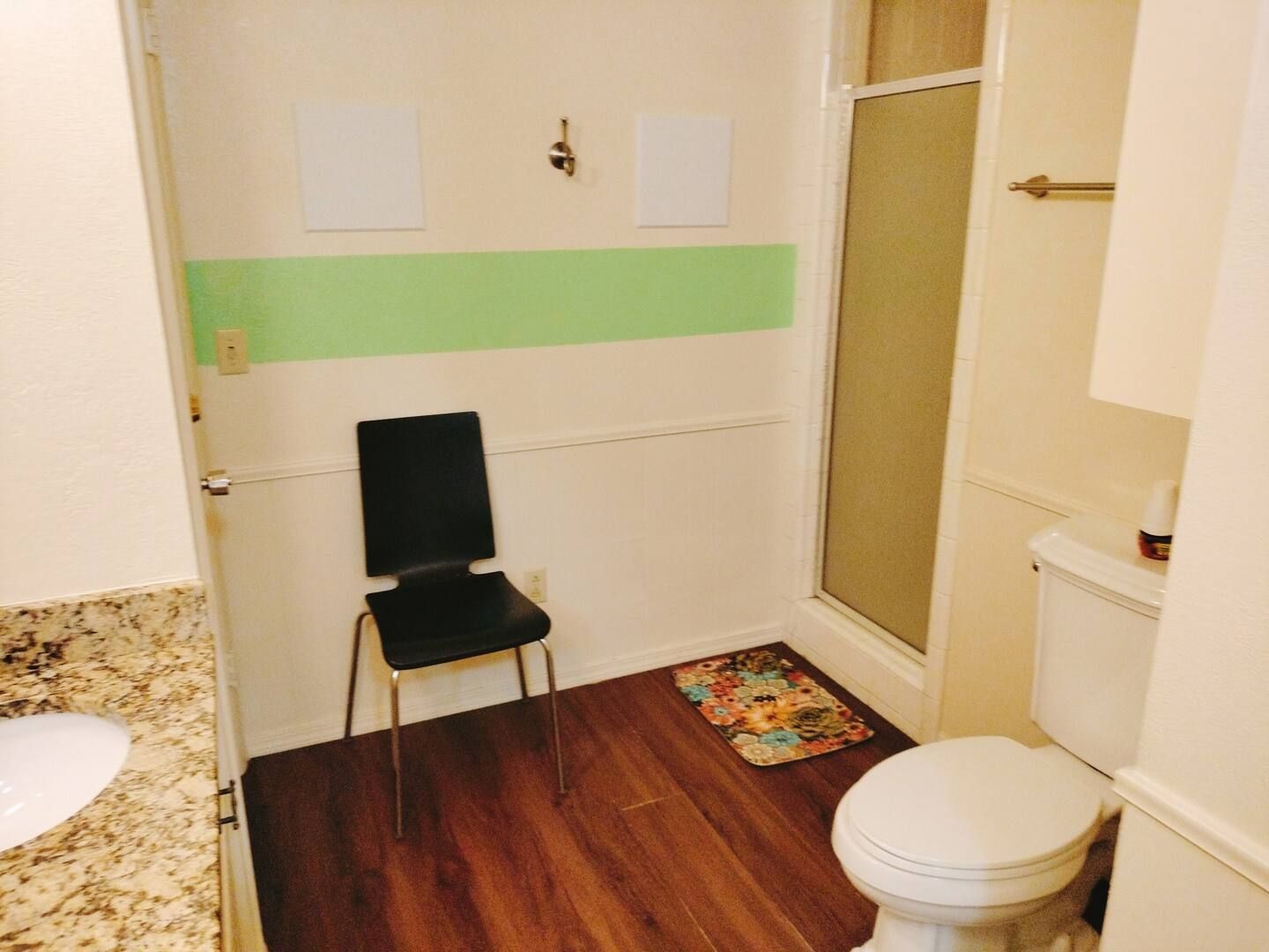 A bathroom with a toilet a sink and a chair