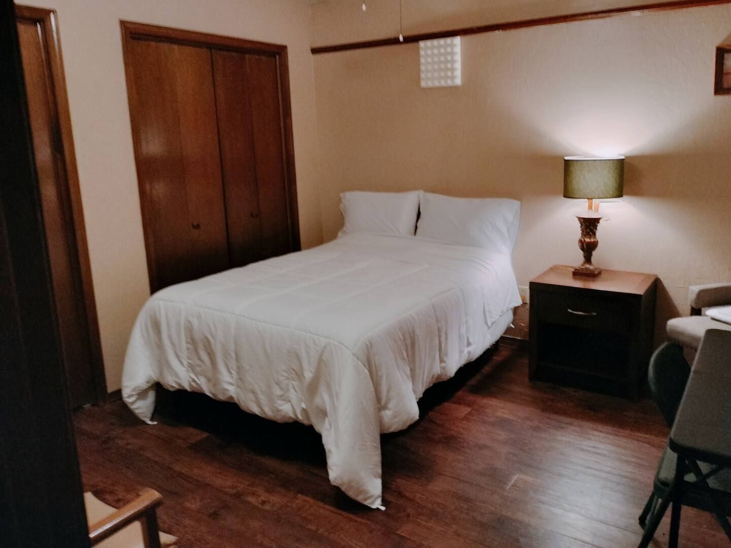 A bedroom with a bed a nightstand and a lamp