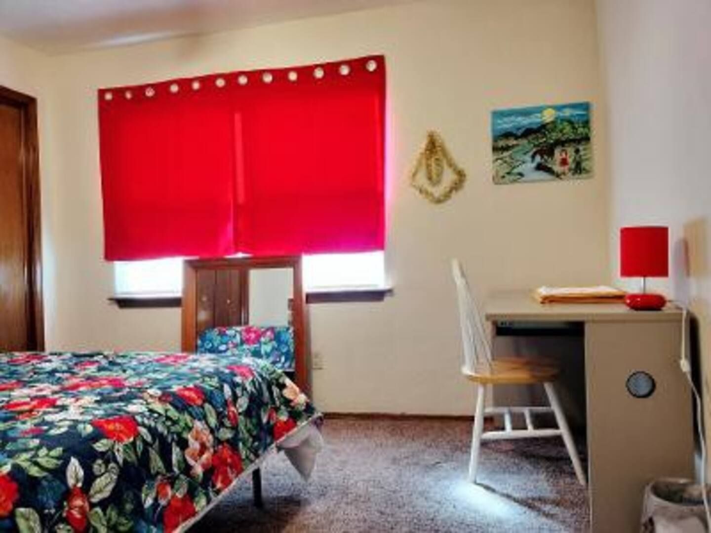 A bedroom with two beds and a desk with a red lamp