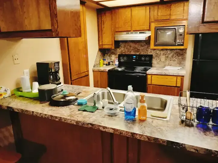 A kitchen with a sink , stove , microwave and refrigerator.