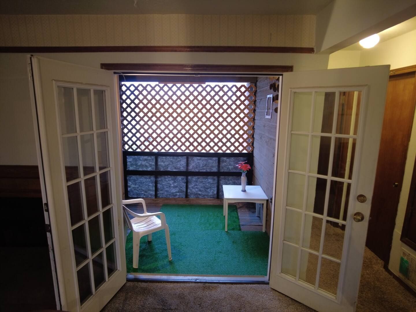 A room with french doors open to a balcony