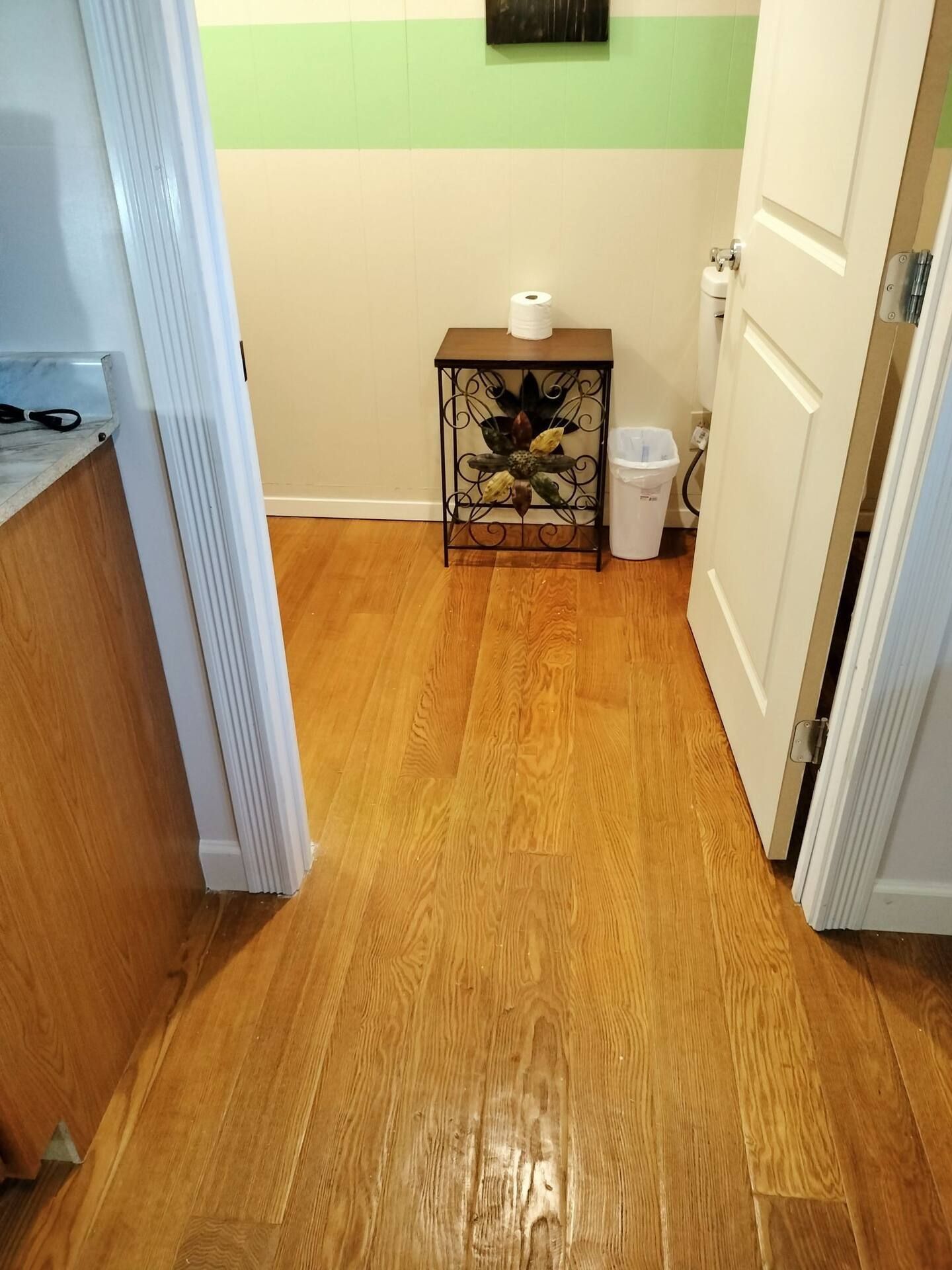 A hallway with hardwood floors and a trash can