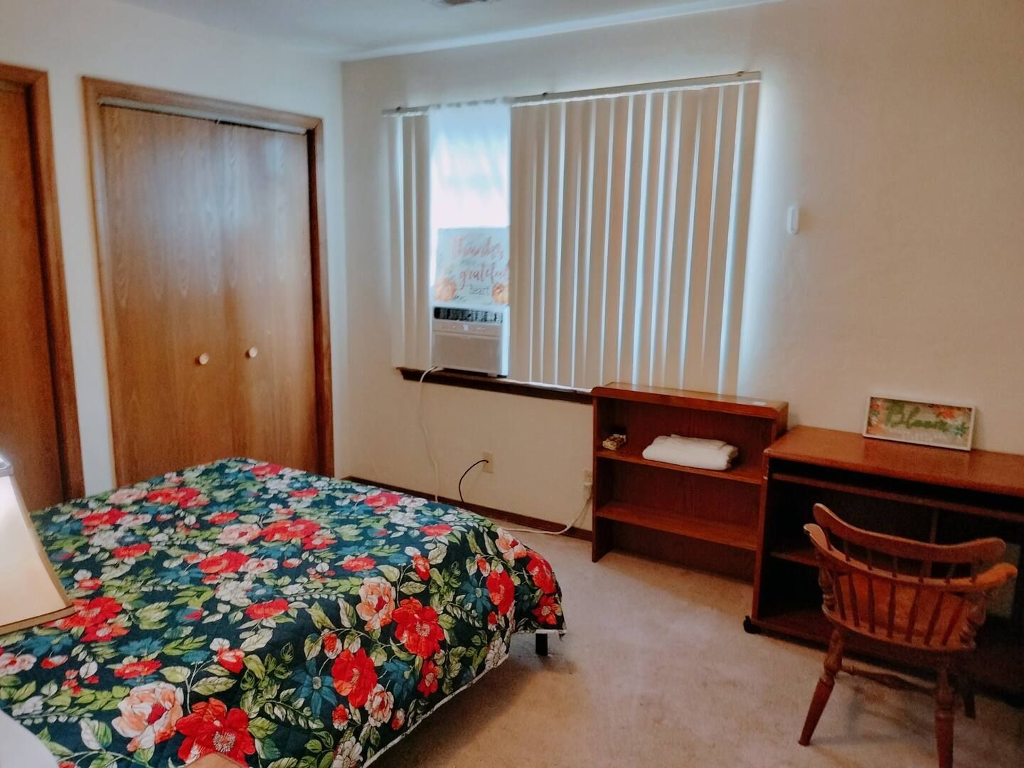 A bedroom with a bed a desk and a window