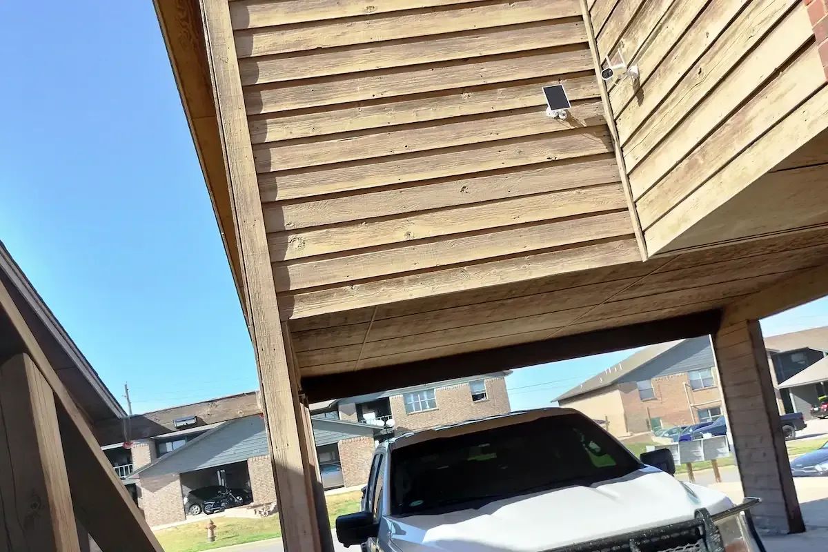 A white truck is parked under a wooden house.