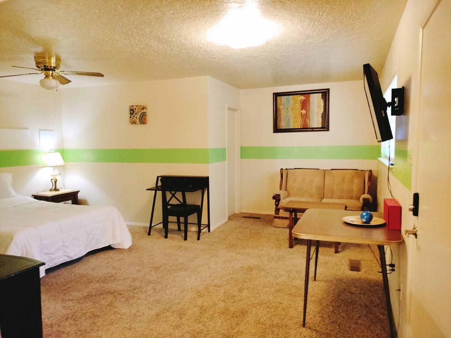 A bedroom with a bed a desk a couch and a television