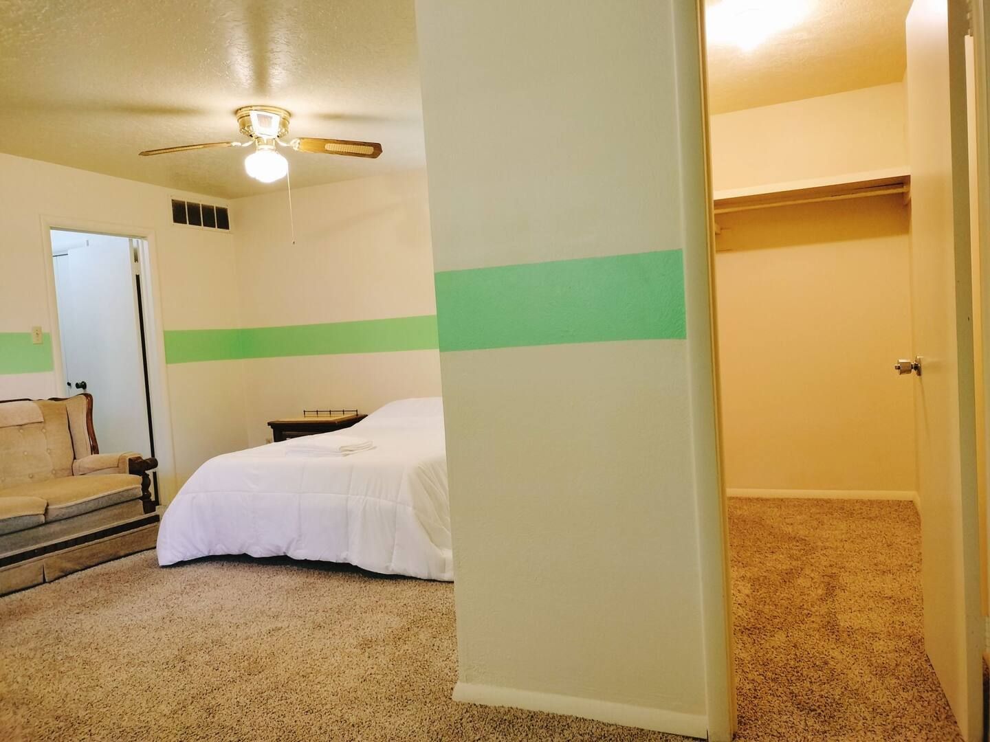 A bedroom with a bed and a ceiling fan