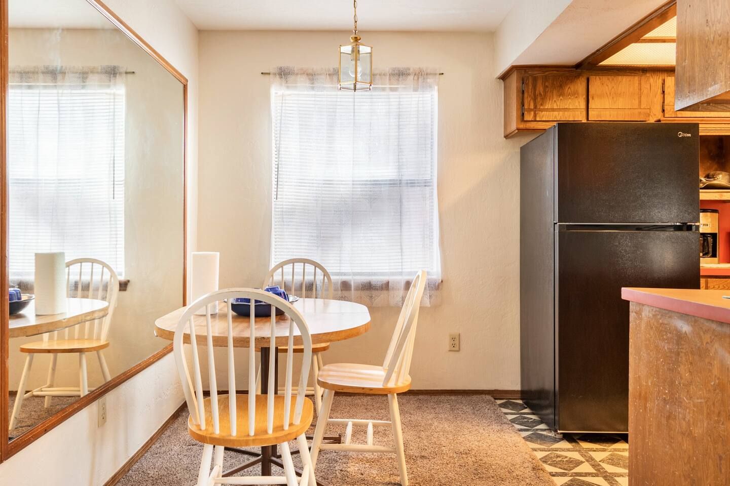A dining room with a table and chairs and a refrigerator.