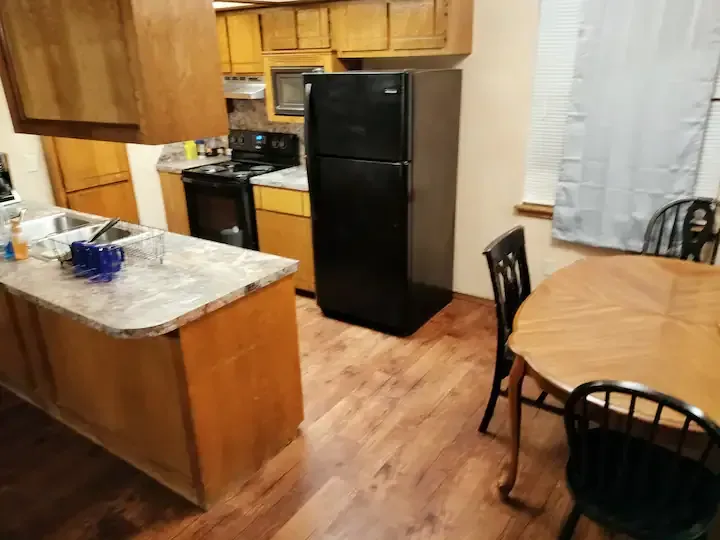 A kitchen with a table and chairs and a black refrigerator