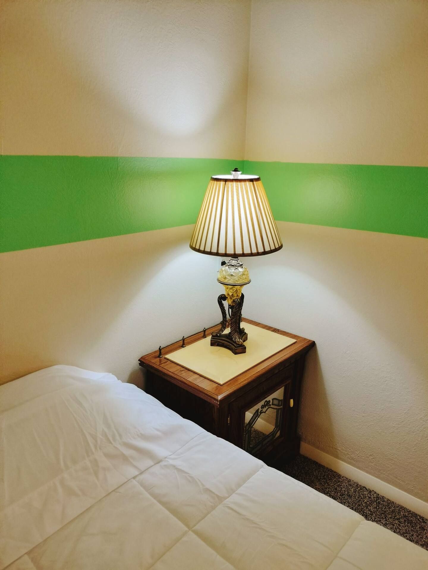 A lamp sits on a nightstand next to a bed