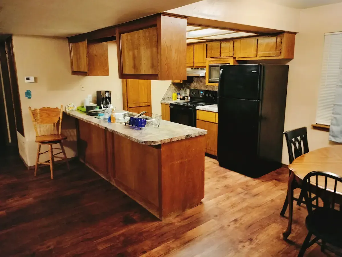 A kitchen with wooden cabinets and a black refrigerator