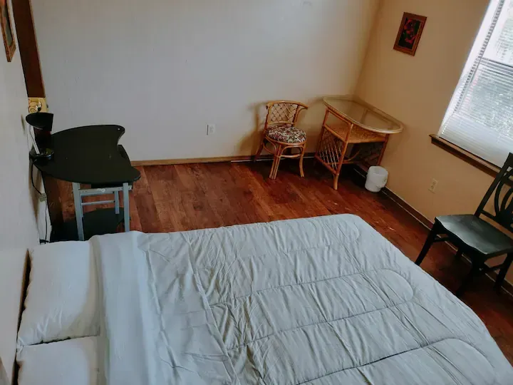 A bedroom with a bed a chair a desk and a window