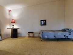 A bedroom with a bed , table , lamp and mirror.