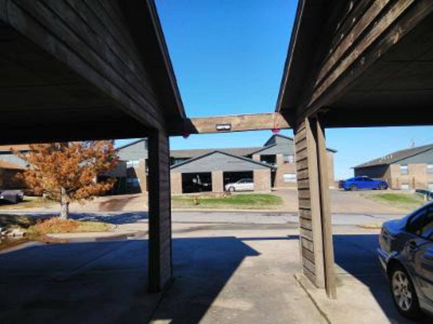 A car is parked under a carport in front of a house