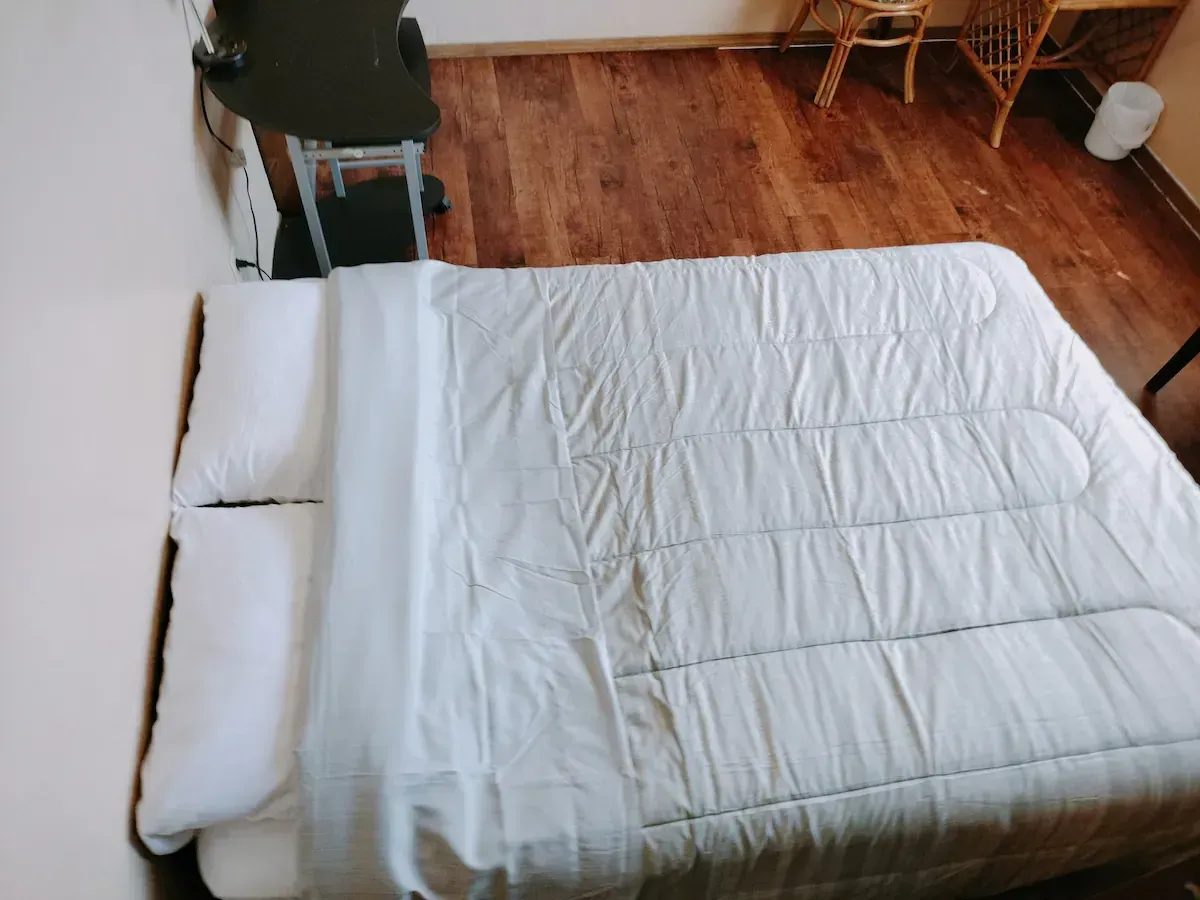 A bed with white sheets and pillows in a bedroom