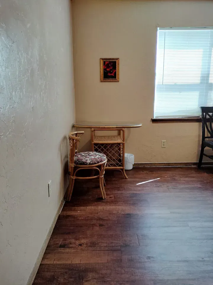 There is a chair and a table in the corner of the room.