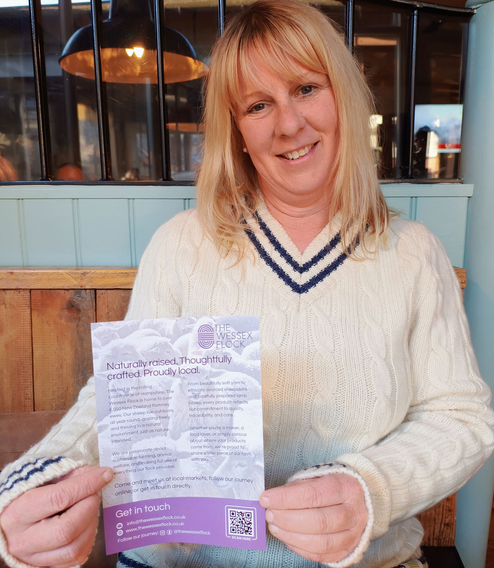 Lady in a wool sweater holding a leaflet while smiling