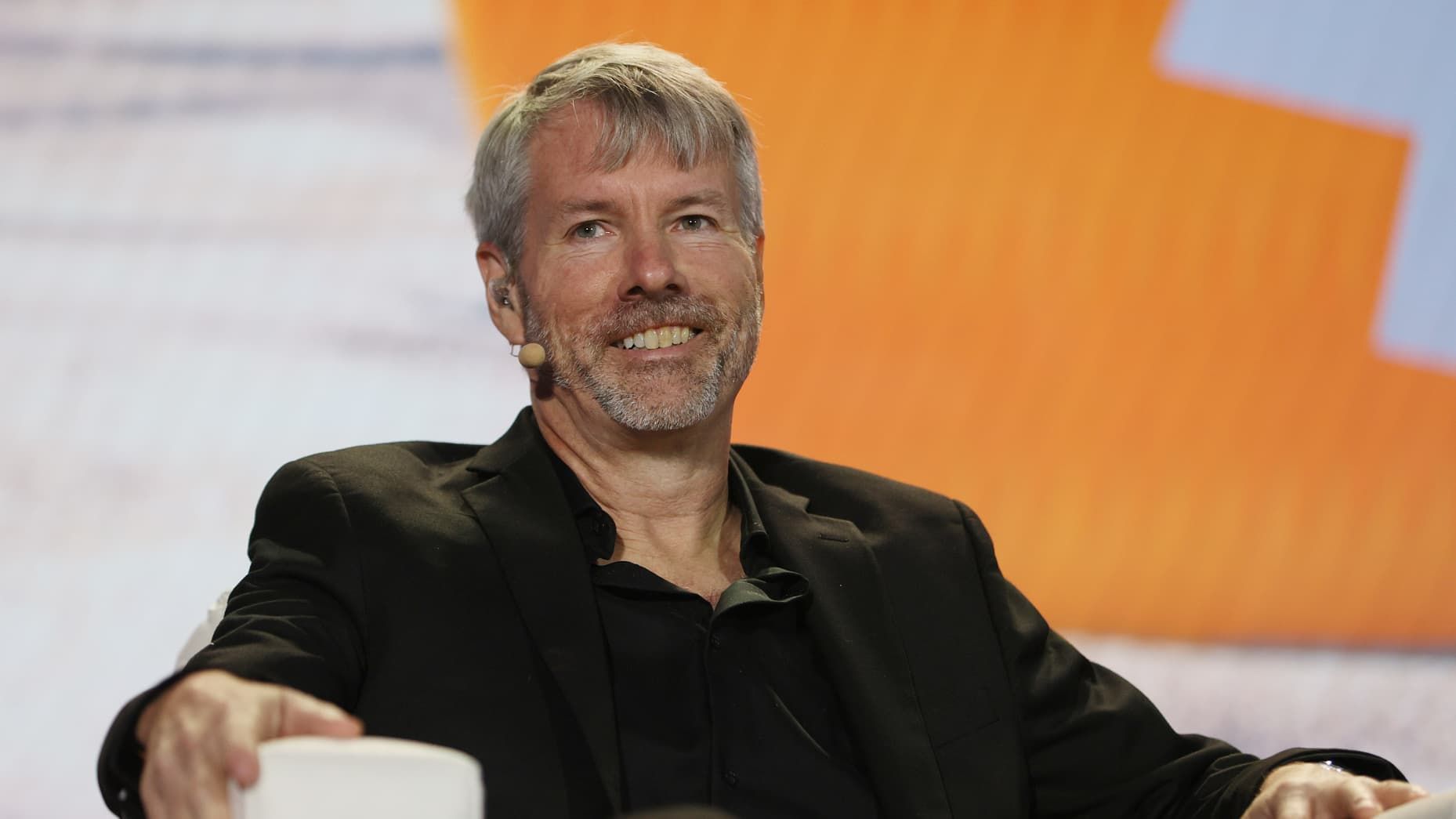 A man with a beard is sitting in front of a microphone and smiling.