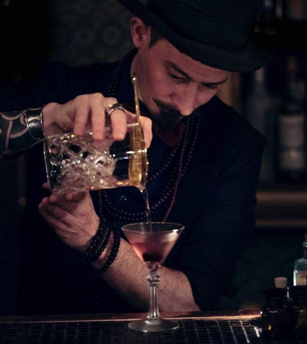A man pouring a drink into a martini glass