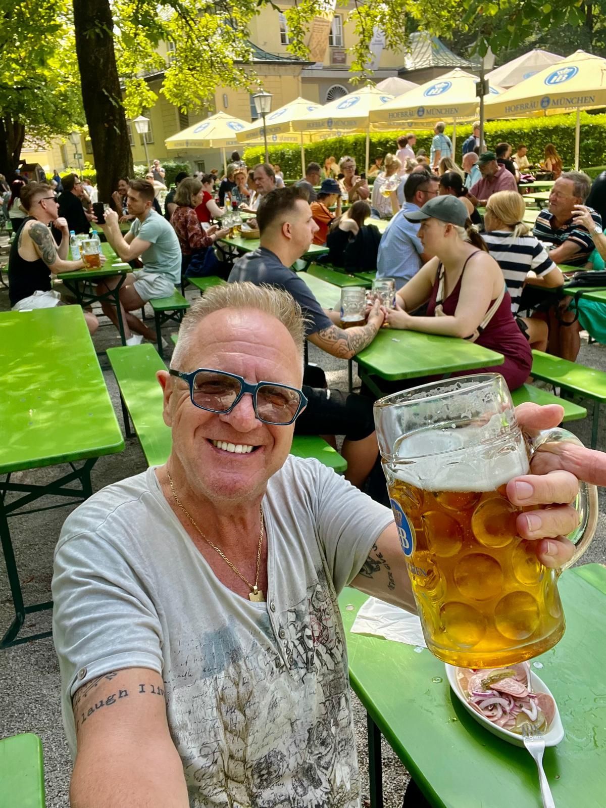 A man is sitting at a table holding a glass of beer.