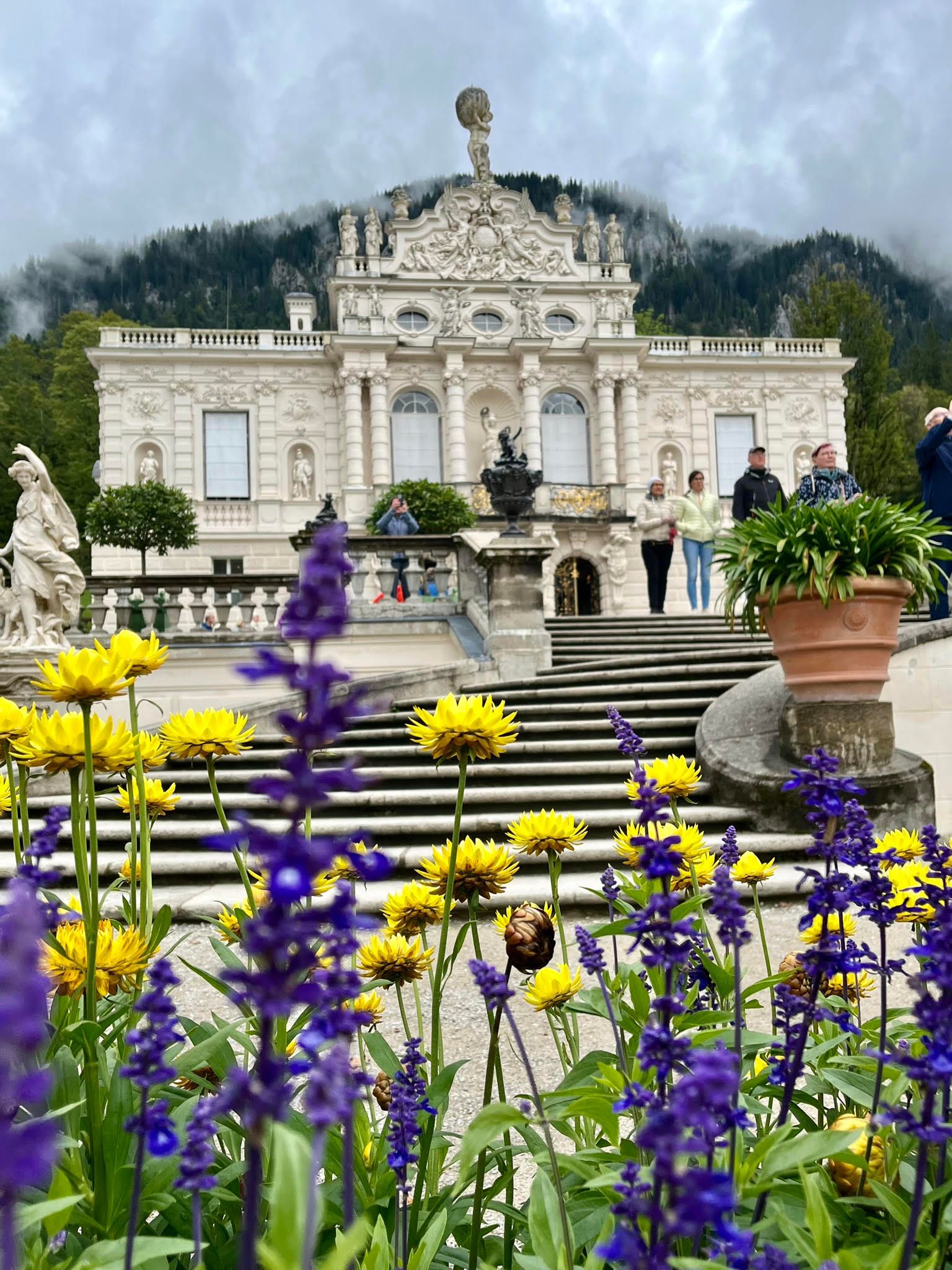 A castle with purple and yellow flowers in front of it.