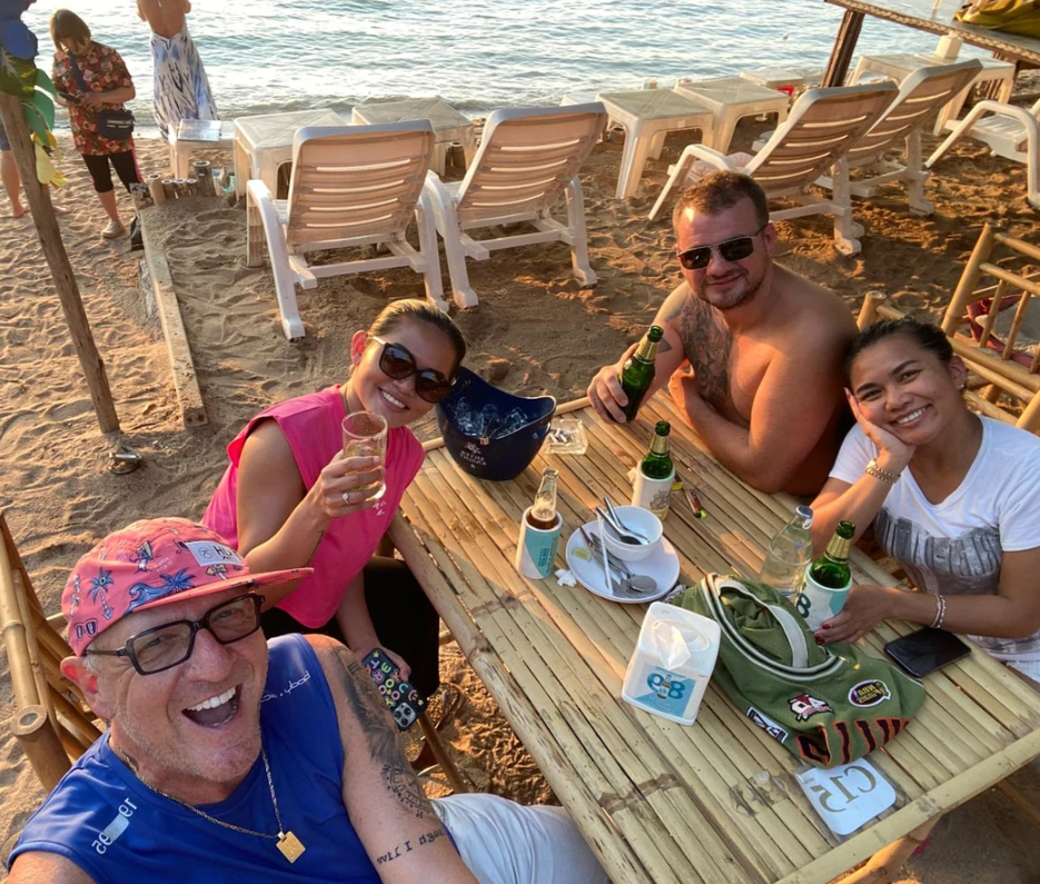 A group of people are sitting at a table on the beach.