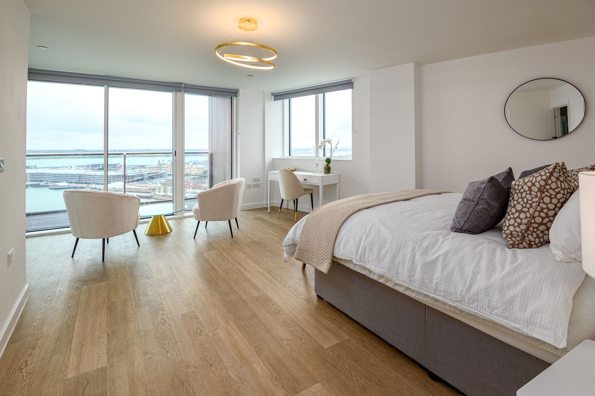 A bedroom with a large bed , chairs , a desk and a large window.